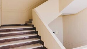 A staircase with a beige wall and a white handrail. - VIDA in Yasmeen - V402, Vida New Standard Studio (New Cairo City)