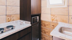 A kitchen with a microwave, refrigerator, and sink. - VIDA in Yasmeen - V402, Vida New Standard Studio (New Cairo City)