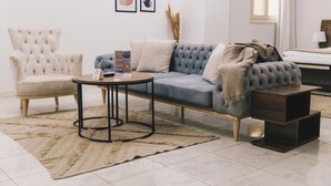 A modern living room with a tufted sofa, a round coffee table, and a side table. - The Seven Six Near Waterway 5A - 12, THE SEVEN SIX near WATERWAY 5A MALL By ELEGANT (New Cairo City)