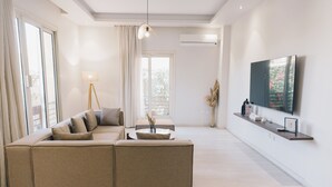Un salon moderne avec un canapé d’angle beige, une table basse et un téléviseur à écran plat fixé au mur.