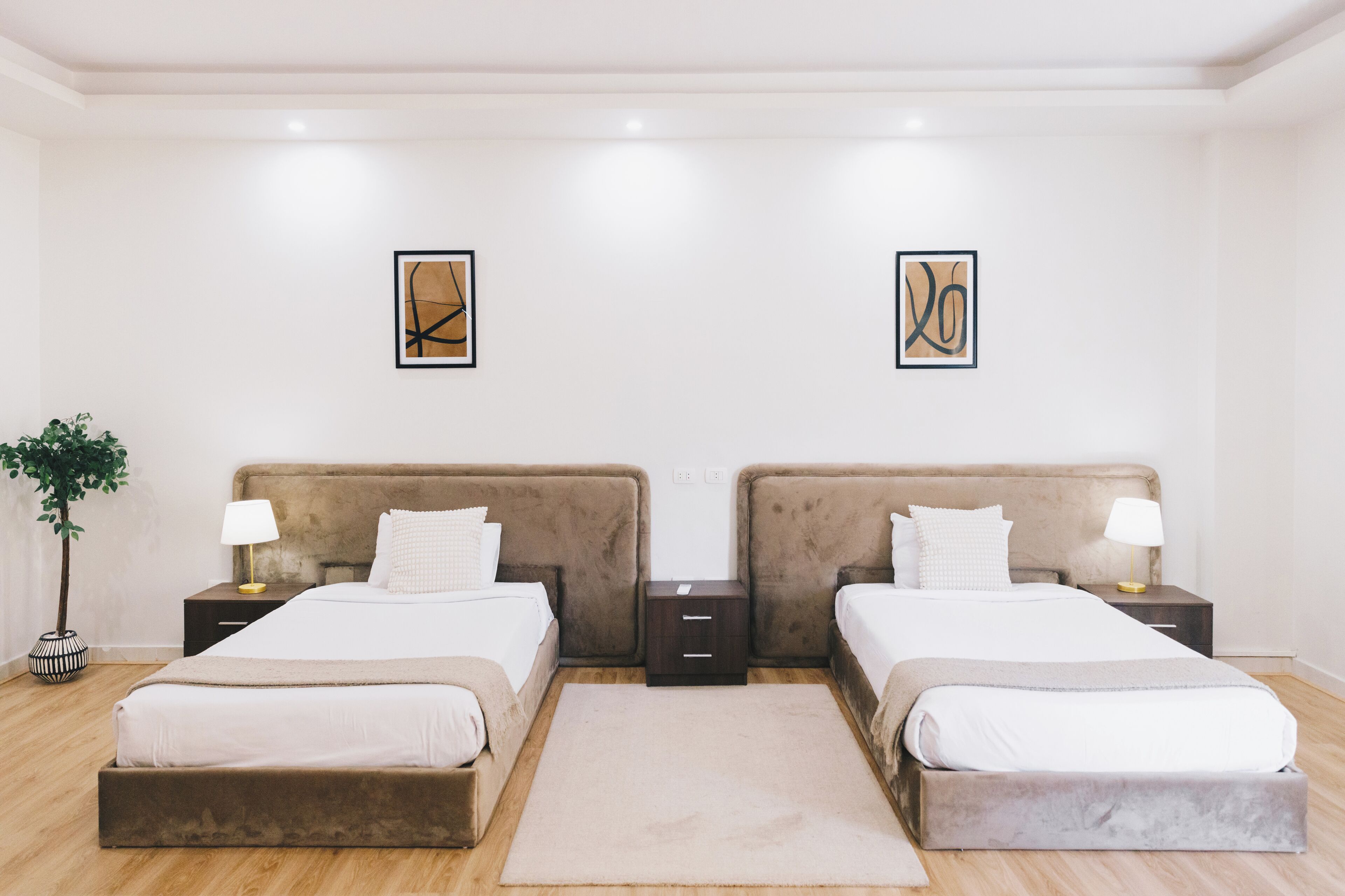 A double room with two beds, bedside tables, lamps, and artwork on the walls.