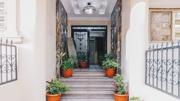 A staircase with potted plants on either side, leading to a door with a decorative gate. - VIOLA Near Waterway - 11, VIOLA New Studio - Higher Floor (New Cairo City)