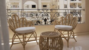 A balcony with wicker chairs and a round table, overlooking a residential area with multi-story buildings. - VIOLA Near Waterway - 21, VIOLA New Studio - Higher Floor (New Cairo City)