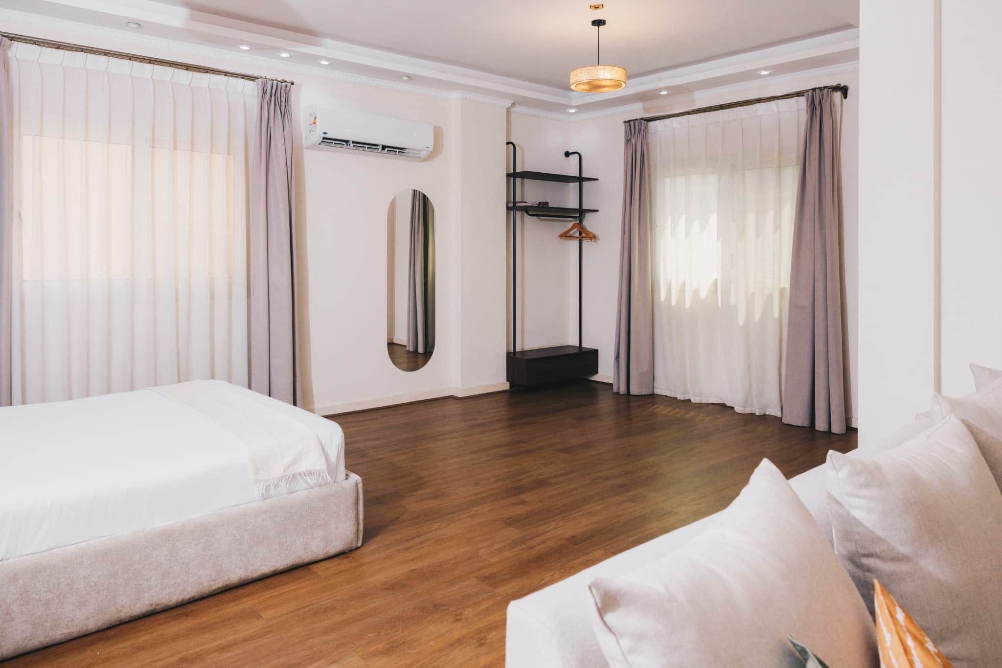 A hotel room with a bed, a sofa, a mirror, and a wardrobe.