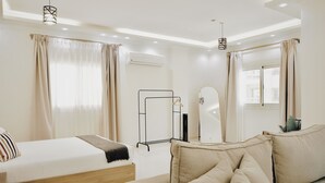 Ein modernes Hotelzimmer mit Bett, Sofa, Spiegel und einem Fenster mit Vorhängen.