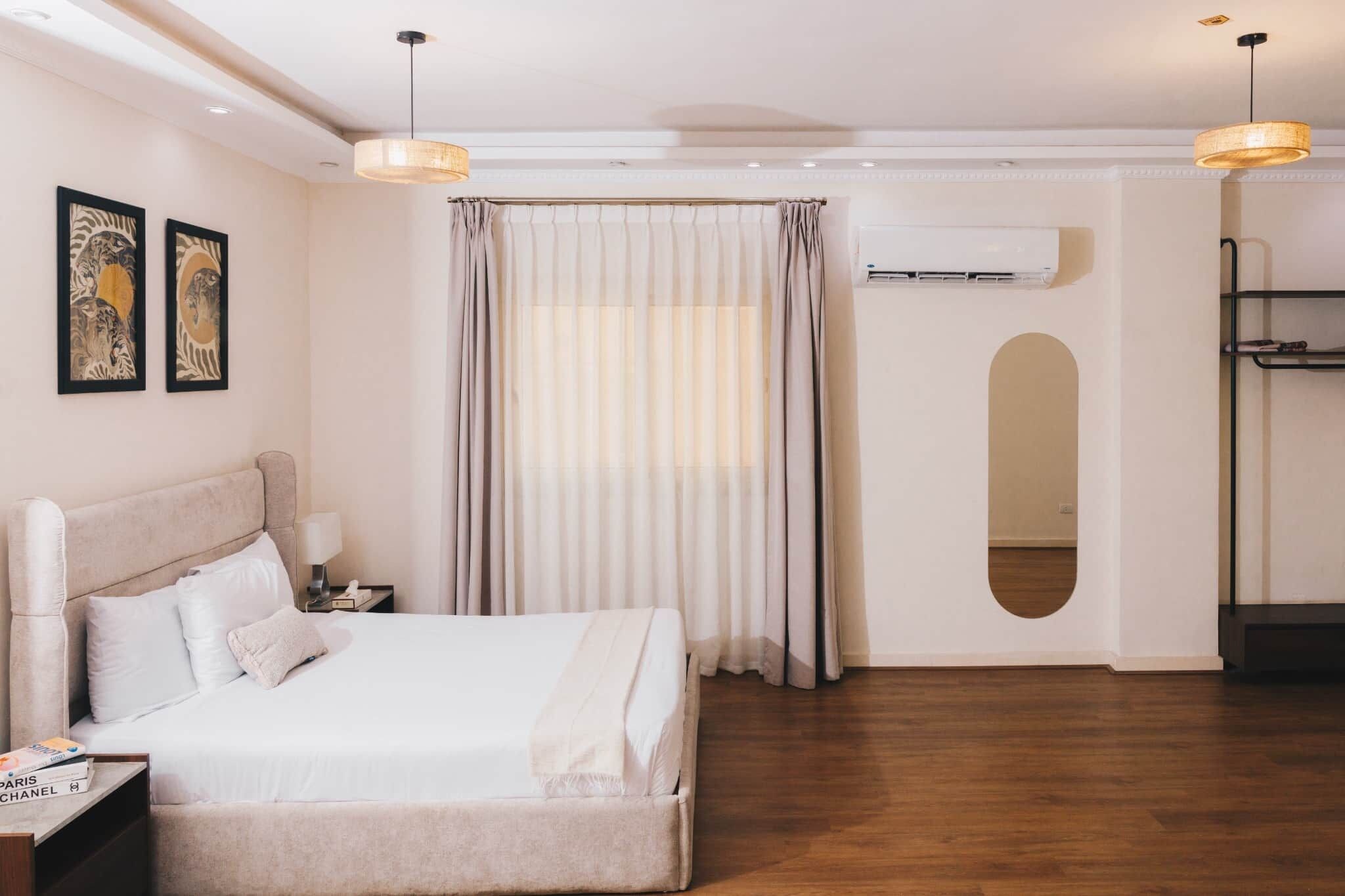 Habitación de hotel con cama, mesita de noche, lámpara, aire acondicionado y armario.