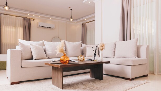 A modern living room with a beige sofa, a wooden coffee table, and decorative items.