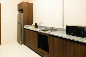 A kitchen with a built-in gas stove, a microwave, and a refrigerator. - VIOLA Near Waterway - 31, VIOLA New Studio - Higher Floor (New Cairo City)