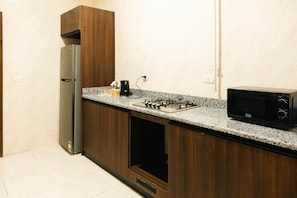 A kitchen with a built-in gas stove, a microwave, and a refrigerator. - VIOLA Near Waterway - 32, VIOLA New Studio - Higher Floor (New Cairo City)