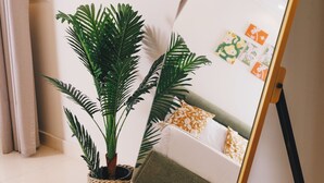 Een kamer met een bloempot, een whiteboard met kleurrijke notities en een bed met een groen kussen.