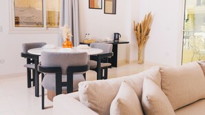 A modern living room with a round dining table, grey upholstered chairs, a beige sofa, and a vase with dried plants. - VIOLA Near Waterway - 02, VIOLA New Studio - Ground Floor (New Cairo City)