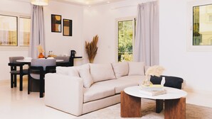 A modern living room with a beige sofa, a round coffee table, and a dining area with a table and chairs. - VIOLA Near Waterway - 02, VIOLA New Studio - Ground Floor (New Cairo City)