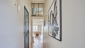 A hallway with a wooden floor, a dining area in the background, and a large abstract painting on the wall. - Amazing Apartment Le Marais Center of Paris (Paris)