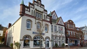 A traditional building with arched windows and a corner turret. - Meeresbrise 2 Top location with terrace. Pet friendly! (Tönning)