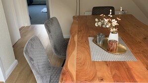 A dining table with a wooden top, grey upholstered chairs, and a vase with flowers. - Meeresbrise 2 Top location with terrace. Pet friendly! (Tönning)