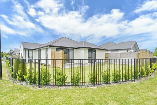 A modern residential complex with multiple houses, a well-maintained lawn, and a metal fence. - Charming 3-Bedroom, 2-Bathroom Home (Woodend)