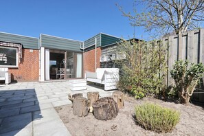 A patio area with a brick wall, a white outdoor sofa, and a wooden fence.