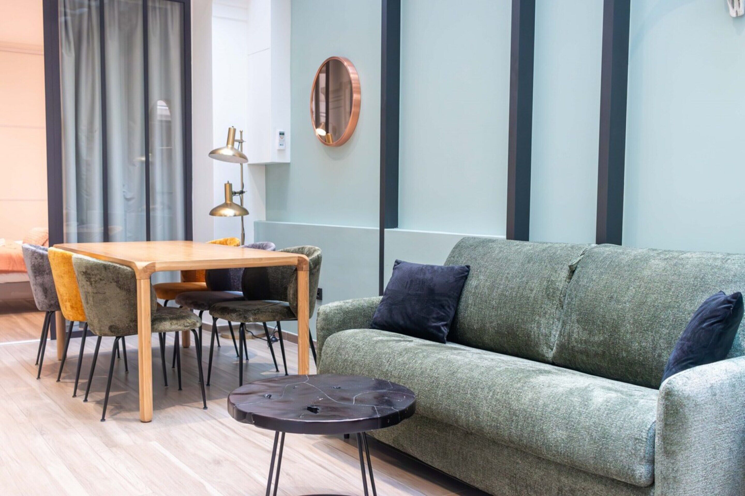 Una sala de estar moderna con un sofá verde, una mesa de comedor de madera y sillas a juego.