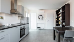 Una cucina moderna con mobili grigi, una cappa in acciaio inossidabile e un'area pranzo con un tavolo e sedie in legno scuro.