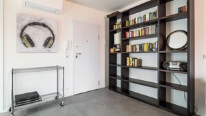 Una stanza con una libreria, una porta bianca e un carrello in metallo.