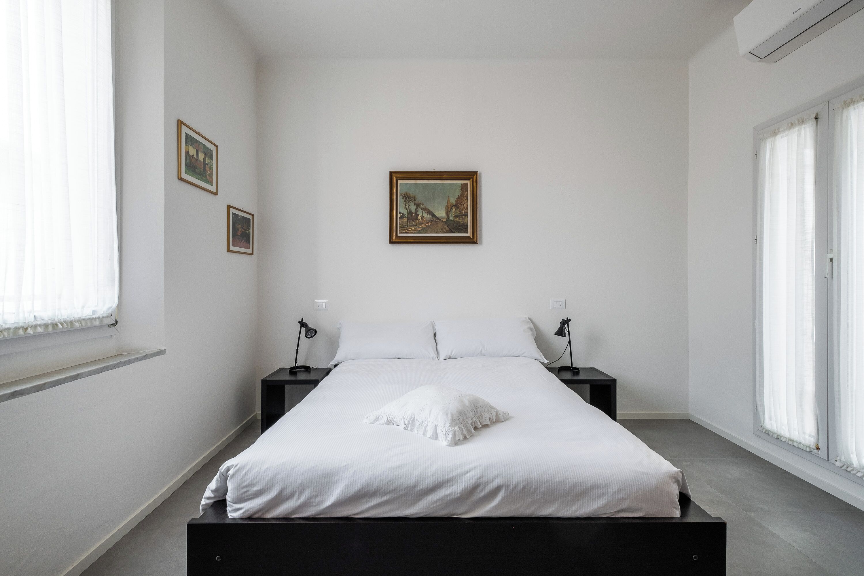 Un dormitorio minimalista con una cama grande, dos mesitas de noche y un cuadro enmarcado en la pared.