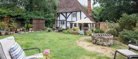 Una casa tradicional de estilo Tudor con un jardín bien cuidado, un banco de piedra y una silla de patio.