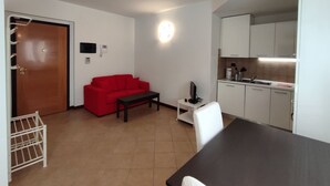A compact living space with a kitchenette, a red sofa, a small table, and a TV. - Leopolda Suite (Florence)
