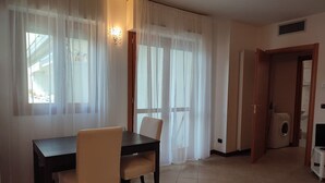 A dining area with a table and chairs, a washing machine in the background, and a door leading to another room. - Leopolda Suite (Florence)