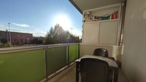 A balcony with a table and chairs, a green railing, and a view of buildings in the background. - Leopolda Suite (Florence)