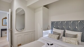 Habitación de hotel con una cama grande, una mesita de noche, un espejo y un cabecero decorativo.