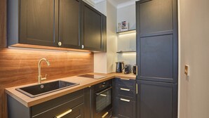 Una cocina moderna con armarios oscuros, encimera de madera, un lavabo y electrodomésticos integrados.