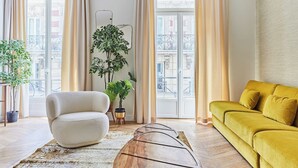 Ein Wohnzimmer mit Sofa, Sessel und Topfpflanzen.