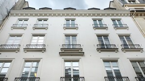 Ein mehrgeschossiges Gebäude mit weißen Fassaden, zahlreichen Fenstern und Balkonen.