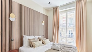 Ein modernes Schlafzimmer mit Bett, Nachttischen und einem Fenster mit Vorhängen.