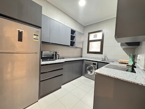 A modern kitchen with stainless steel appliances, grey cabinets, and a granite countertop. - Mynt Stay New Cairo Residence (New Cairo)