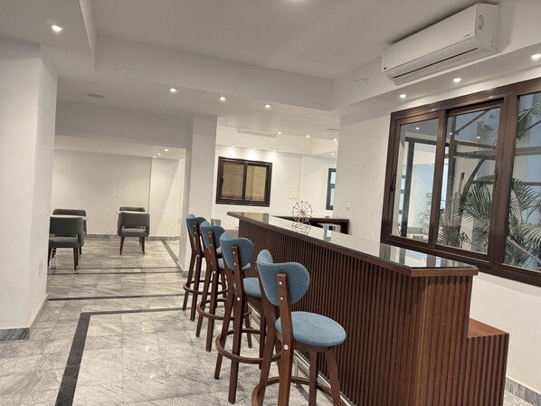 A modern reception area with a wooden counter, bar stools, and a large window. - Mynt Stay New Cairo Residence (New Cairo)