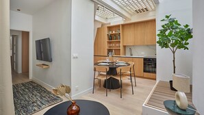 A modern kitchen with wooden cabinets, a dining table set for four, and a small plant on the right. - Sublim Apartment Le Marais Centre de Paris (Paris)