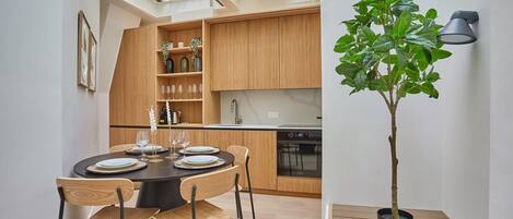 Une cuisine moderne avec des meubles en bois, une table à manger pour quatre personnes et une plante en pot.