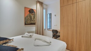 A modern hotel room with a large bed, a desk, and a wooden wardrobe. - Sublim Apartment Le Marais Centre de Paris (Paris)