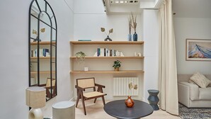 A modern living room with a round table, a bookshelf, a chair, and a sofa. - Sublim Apartment Le Marais Centre de Paris (Paris)