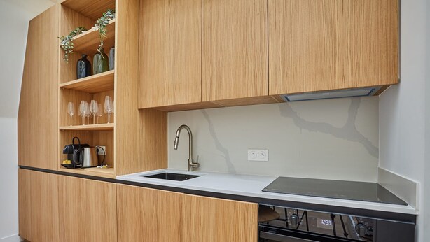 Une cuisine moderne avec des meubles en bois, un plan de travail noir, un évier en acier inoxydable et un four encastré.