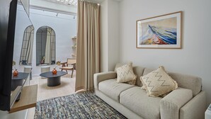 A living room with a sofa, a television, a coffee table, and a painting on the wall. - Sublim Apartment Le Marais Centre de Paris (Paris)