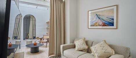 Uma sala de estar com sofá, televisão, mesa de centro e um quadro na parede.