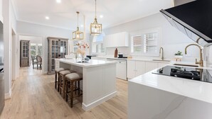 A modern kitchen with a central island, white cabinetry, and pendant lighting. - Harbourfront Haven –4BR Retreat with Stunning Views of Sydney’s Iconic La... (Cremorne Point)