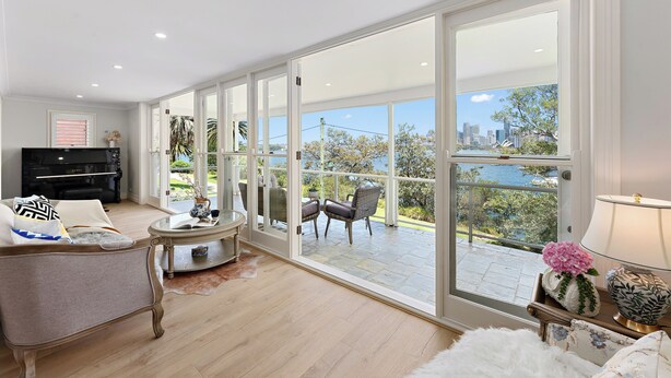 A spacious living room with a piano, comfortable seating, and a large sliding glass door leading to an outdoor patio with a city view. - Harbourfront Haven –4BR Retreat with Stunning Views of Sydney’s Iconic La... (Cremorne Point)