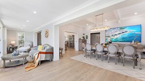 A spacious living room with a dining area, a large flat-screen TV, and a chandelier. - Harbourfront Haven –4BR Retreat with Stunning Views of Sydney’s Iconic La... (Cremorne Point)