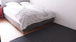 A neatly made bed with a fluffy white blanket and a grey headboard. - Antique Rentals (Reykjavik)