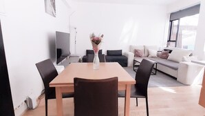 A modern living room with a dining table, sofas, and a TV. - Antique Rentals (Reykjavik)