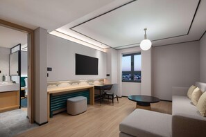 A modern hotel room with a bed, a desk, a chair, a small table, and a large window. - Hilton Garden Inn Chengde Mountain Resort (Chengde)