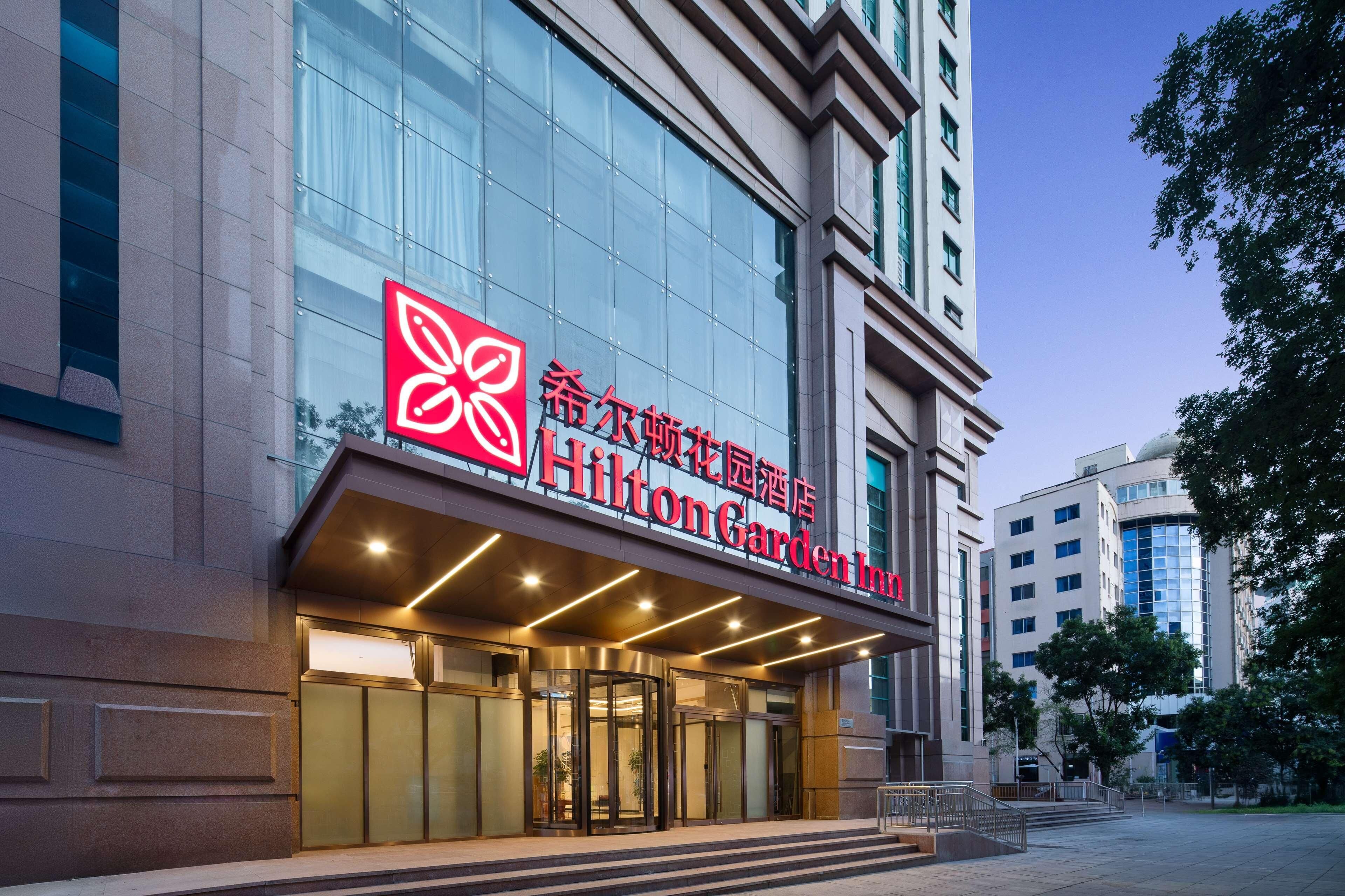 A Hilton Garden Inn with a modern facade, large glass windows, and a prominent red logo.